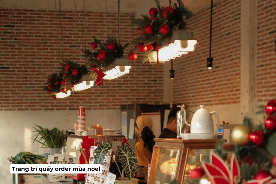 Ý tưởng trang trí Noel cho quán Cafe đẹp, hút khách năm 2026 8 Trang trí bằng nhánh thông và quả châu lên đèn treo khu vực quầy